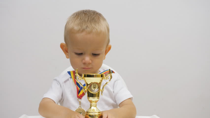 Funny baby child winner holding champion golden cup and pointing with finger to looser, confident kid smiling enjoy victory taste, conceptual Royalty-Free Stock Footage #1023376738