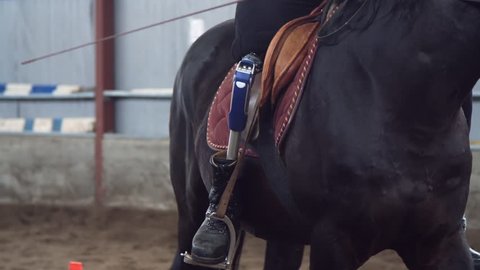 close-up, artificial leg, limb in stirrups. male rider, disabled person, without leg, learns to ride horse, hippotherapy. concept of rehabilitation of disabled with animals.