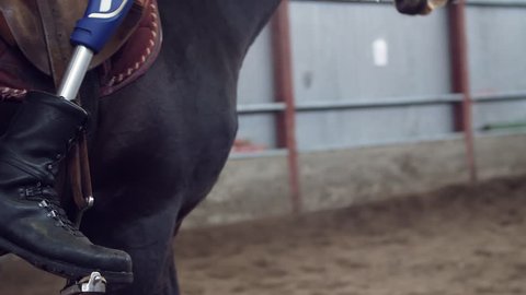 close-up, artificial leg, limb in stirrups. male rider, disabled person, without leg, learns to ride horse, hippotherapy. concept of rehabilitation of the disabled with animals.