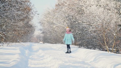 little girl runs on a snowy road