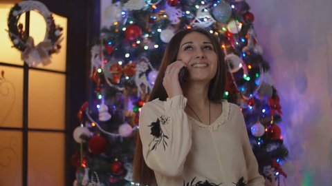 girl talking on the phone on the background of the Christmas tree