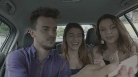 Cheerful students having fun when they travel in the car taking selfie pics and video streaming with digital phone cheering and dancing together