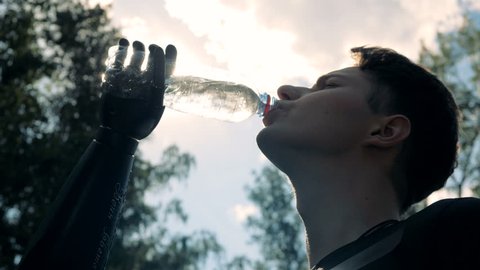 Man drinks water on a sky background, bottom view.
