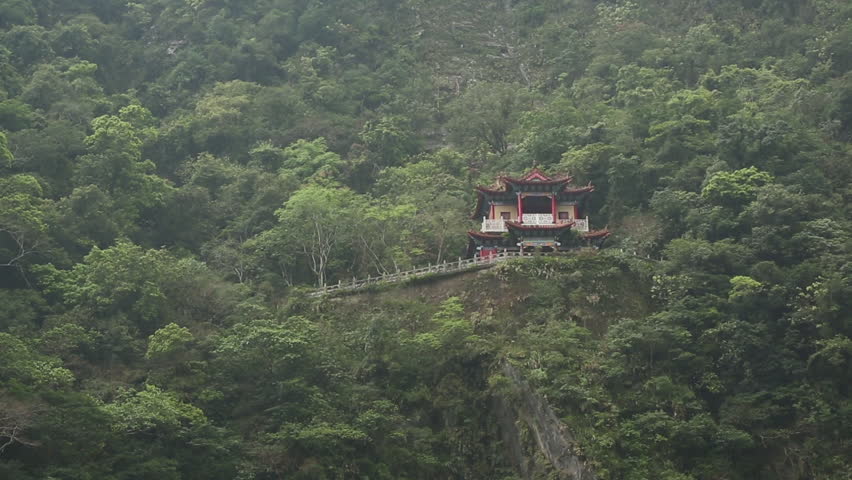 Buddhist shrine structure built into side of lush green mountain in East Asia Taiwan