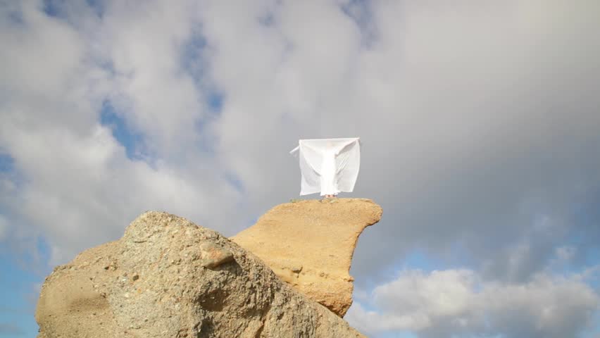 Freedom Concept . Women in white dress and with scarf standing on the Rock. Dancing. Flying. Moving.
