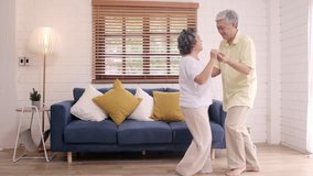 Asian elderly couple dancing together while listen to music in living room at home, sweet couple enjoy love moment while having fun when relaxed at home. Lifestyle senior family relax at home concept. - Powered by Shutterstock - Get 15% off with code: PIKWIZARD15