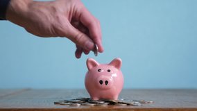 piggy bank saving business standing on a pile of coins concept. A hand is putting a coin in piggy bank. saving money is an investment for the future. Banking investment  business  - Powered by Shutterstock - Get 15% off with code: PIKWIZARD15