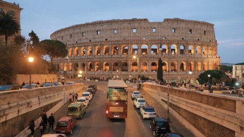 Rome, Italy. Colosseum Also Known As Flavian Amphitheatre. Traffic In Rome Near Famous World Landmark In Evening Time