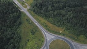 Roundabout circle with moving cars near the forest on a country track. Clip. Aerial view