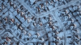 Aerial drone footage of a suburban community in Canada after a blizzard snow storm.  Snow fills the field of view and everything is coated in white.