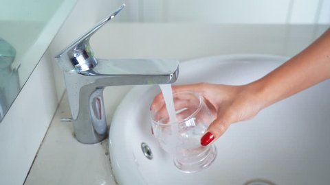 Closeup shot of woman hand pouring a glass of water from a water tap. Shot in 4k resolution