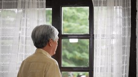 Portrait senior asian man talking on smartphone happy and smiling beside window at home.