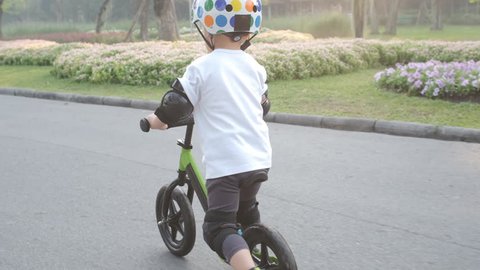 Cute little Asian 2 - 3 years old toddler baby boy child wearing safety helmet learning to ride first balance bike in sunny summer day, kid playing & cycling at park, Cycling with young kids concept