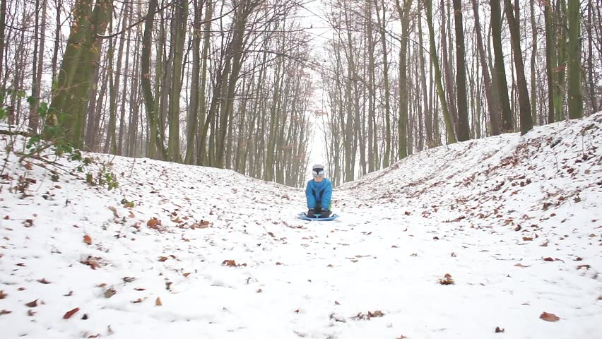 children are riding down a hill on a sled in winter