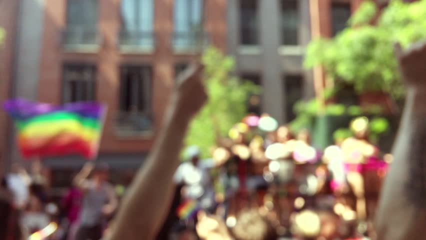 Rainbow flags flying on a float and in the hands of spectators on the sidelines in a defocus view of a summer gay pride parade in Greenwich Village New York City Royalty-Free Stock Footage #1023432379