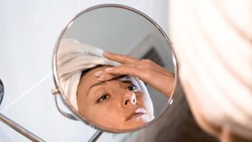 The woman applying face cream on skin. Caucasian female in front of make-up mirror