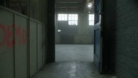 Slow camera move through door frame revealing contemporary dancer dancing in industrial warehouse. Filmed with RED Dragon 6K camera