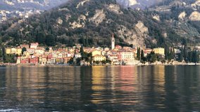 View from a boat of the shores of Lake Como with the town of Varenna and the Italian Alps in background, 4k footage video.
