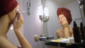 beautiful girl with towel on her head removes makeup