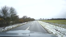 video of the road while driving. oncoming car. the car moves on an asphalt road. snow covers green grass. road signs. Denmark. Winter. movement at speed. country. drive a car	
