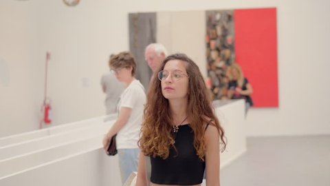 young woman looks at the works exhibited in a contemporary art museum
