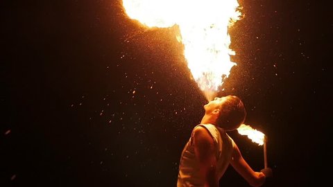 Enjoyment concept entertaining tourists. Professional actor showing flamy spectacle. Young man standing and diffuse in air flaming splash from mouth. Riskily workmanship presentation at darkness area