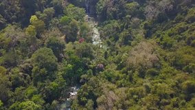 Aerial Drone Footage View: Flight over jungle forest with Kuang Si Falls in Laos.