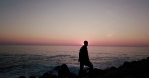 4k beautiful video  black silhouette of a man standing on a beach rocks and observing the sea sunrise or sunset espinho Portugal