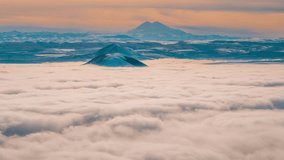 4K quality footage. A beautiful ocean of clouds moves past the tops of the mountains. Scenic view above the clouds, above the sky. On the horizon is the Caucasian ridge and the highest mountain in