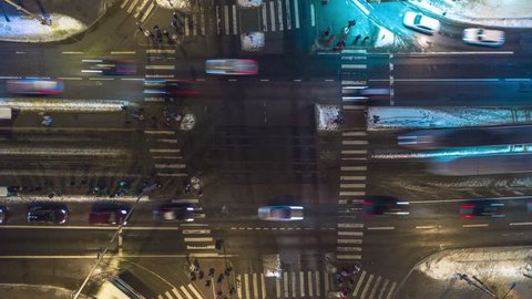 Loopable 4K aerial timelapse of a busy intersection at night with pedestrians, cars, trams and buses. Aerial top-down view of a junction with heavy rush hour city traffic