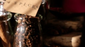 Various exotic spices in glass jar and paper label tag with SPICES text on wooden board. Selective focus. Tracking shot.