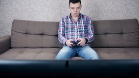 Funny young man sitting on a couch playing video games.