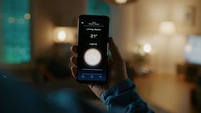 Close Up Shot of a Smartphone with Active Smart Home Application. Person is Giving a Voice Command and Light Turns On in the Room. It's Cozy Evening in the Apartment. - Powered by Shutterstock - Get 15% off with code: PIKWIZARD15