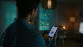 Young Handsome Man Gives a Voice Command to a Smart Home Application on His Smartphone and Lights in the Room are Being Turned On. He is Impressed by Technology. It's a Cozy Evening. - Powered by Shutterstock - Get 15% off with code: PIKWIZARD15