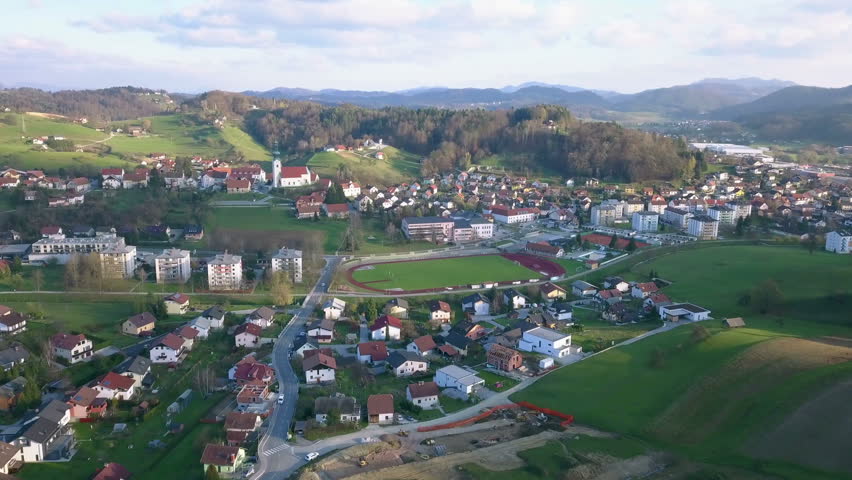 Aerial: Flying over catholic church with big parking place beside. Filming small village on beautiful spring sunny day.