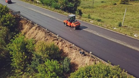Aerial view. Laying a new asphalt on the road. Road repair machine with heavy vibration roller compactor