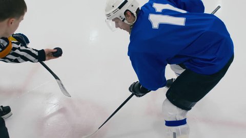 High angle shot of referee throwing puck to face-off on ice hockey game