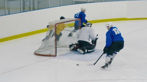 High angle shot of goalie protecting his ice hockey goal, but is being distracted by traffic and conceding a goal