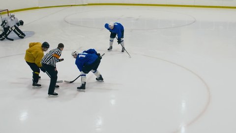 High angle shot of throwing puck to face-off, then shooting a goal fast in ice hockey game on ice arena