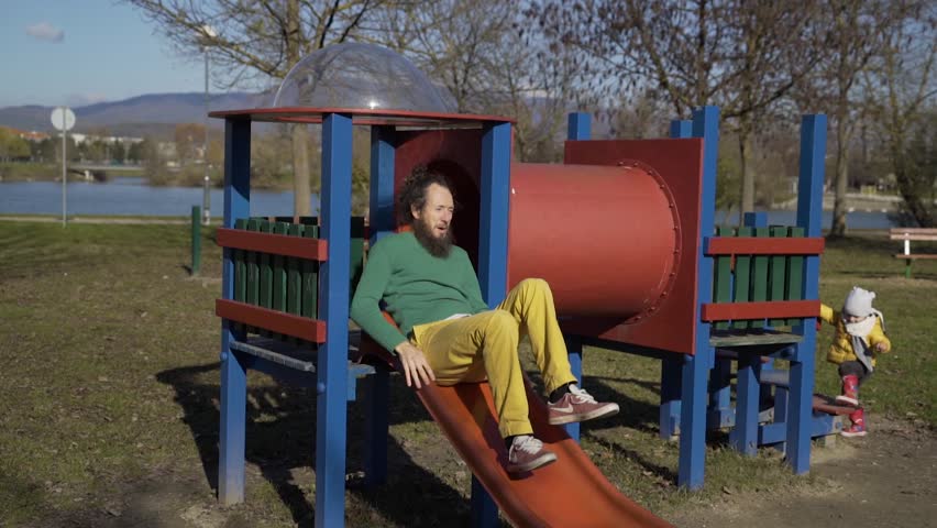 Father sliding in public playground, Zagreb, Croatia.