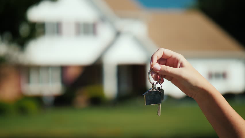 The hand holds the keys to the house. Against the background of a slightly blurred typical American house Royalty-Free Stock Footage #1023514222
