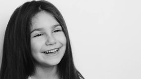 Happy smiling child girl with dark long hear. Beautiful face. Toothless. Black and white video.