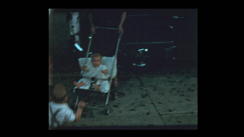 1954 Grandmother with 3 grandchildren pose for camera next to antique car