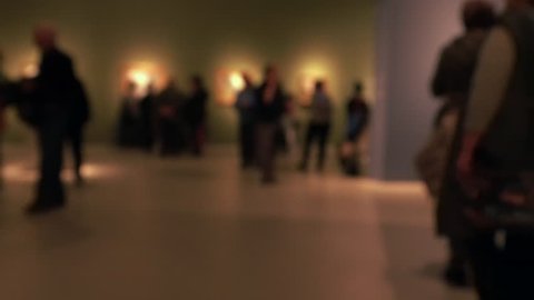 View of people walking during an art gallery exhibition visit. Background with an intentional blur effect applie. 4K