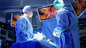 European Caucasian surgical team in scrubs performing laparoscopic surgery on the patient in operating theatre using video camera technology 