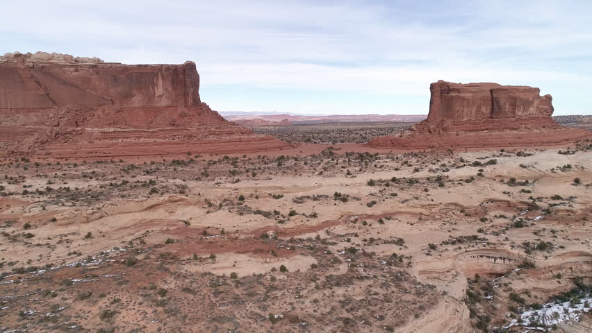 Aerial view flying away from the Monitor and the Merrimac Buttes viewing the canyons in the desert terrain near Moab Utah.