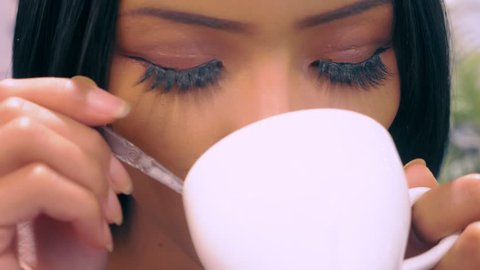 Young attractive Asian girl, ladyboy drinking coffee, sitting at a table in a cafe, close-up lips