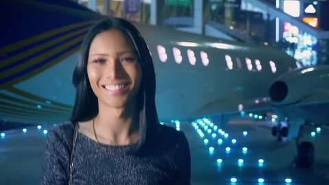Beautiful Asian girl ladyboy looking at the camera and smiling. Thai transgender model at the airport on the background of an airplane in the evening