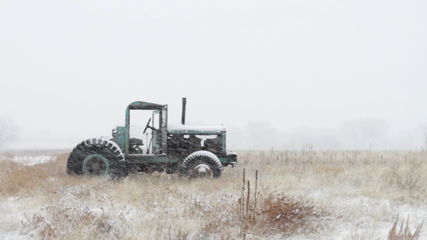 Old green tractor in a snowstorm in rural Colorado. HD 1080p.