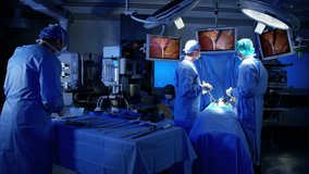 Laparoscopic surgical operation transmitted on hospital video monitors being performed by Caucasians training as surgeons wearing surgical gloves and scrubs RED DRAGON